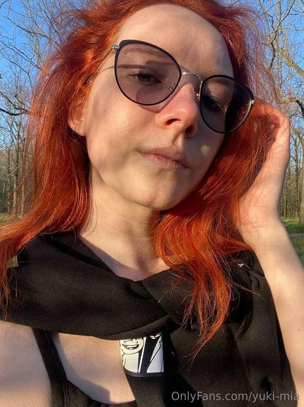 Amidst the greenery of the park, her fiery red locks cascade..