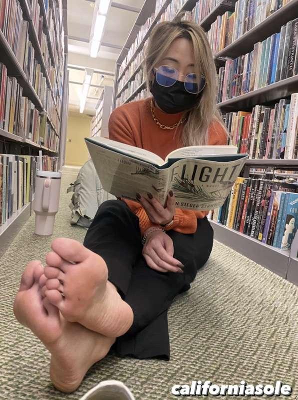 Studious Asian bookworm shows soles in the library
