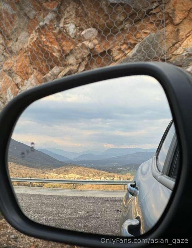 In the reflective embrace of the rearview mirror, a breathta..