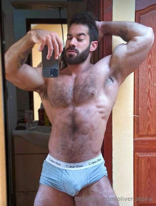 Mirror’s catching every inch biceps flexed, boxers tight, an..