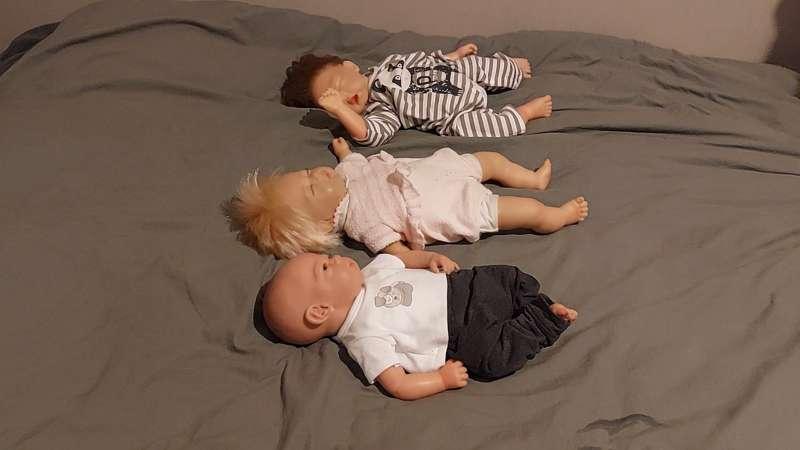 3 realistic  dolls get trampled into the bed. 