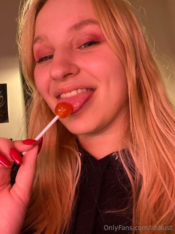 Enjoying a sweet treat, she savors the lollipop's delightful..